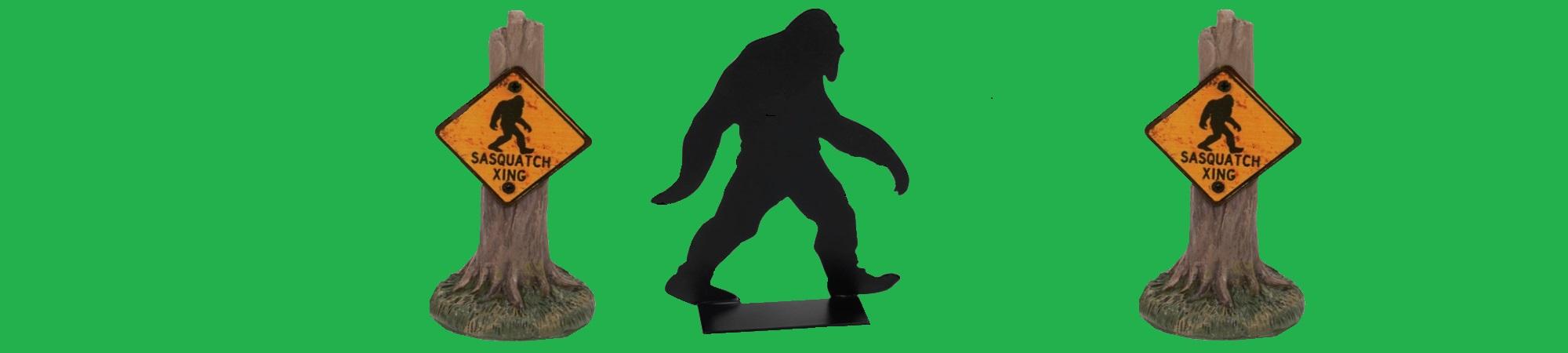 Silhouette of Sasquatch walking. 2 warning signs, "SASQUATCH CROSSING"