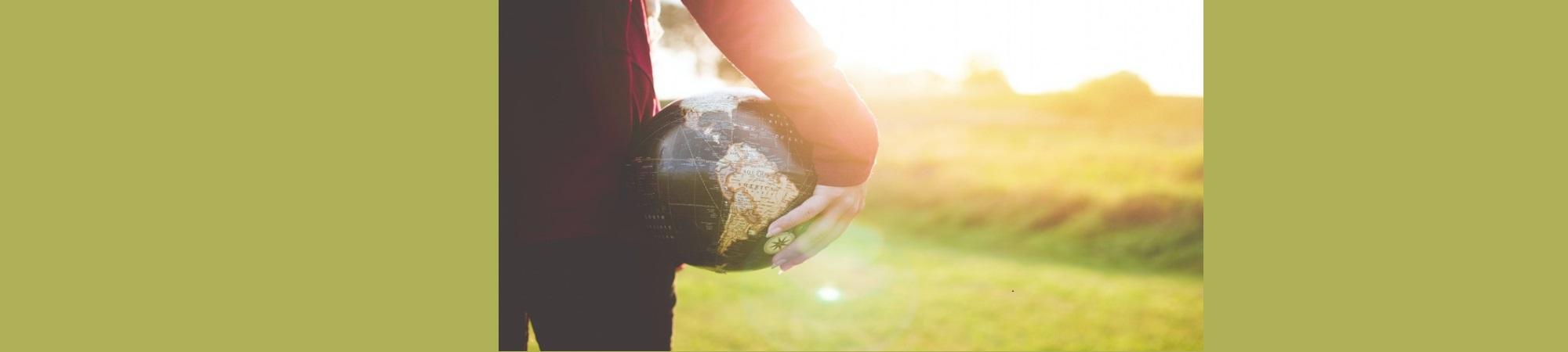Woman carrying globe into an afternoon Sunscape.
