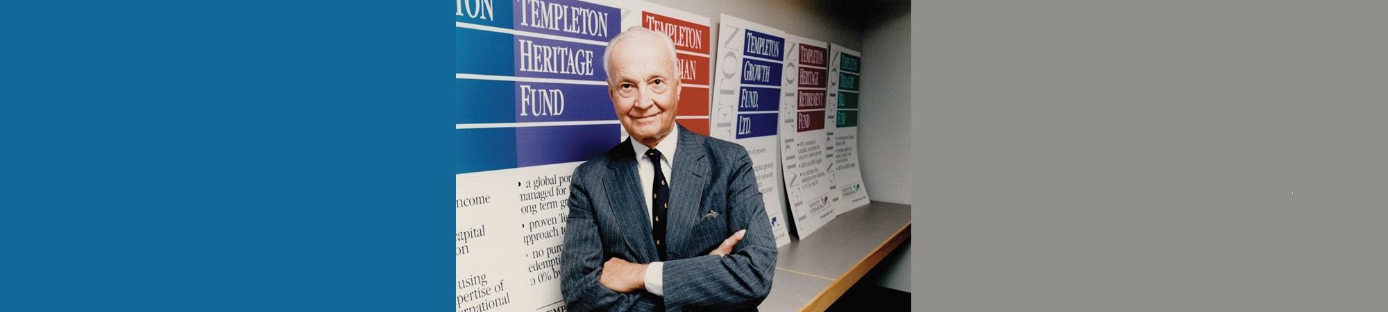 John Templeton in front of posters describing stock funds.