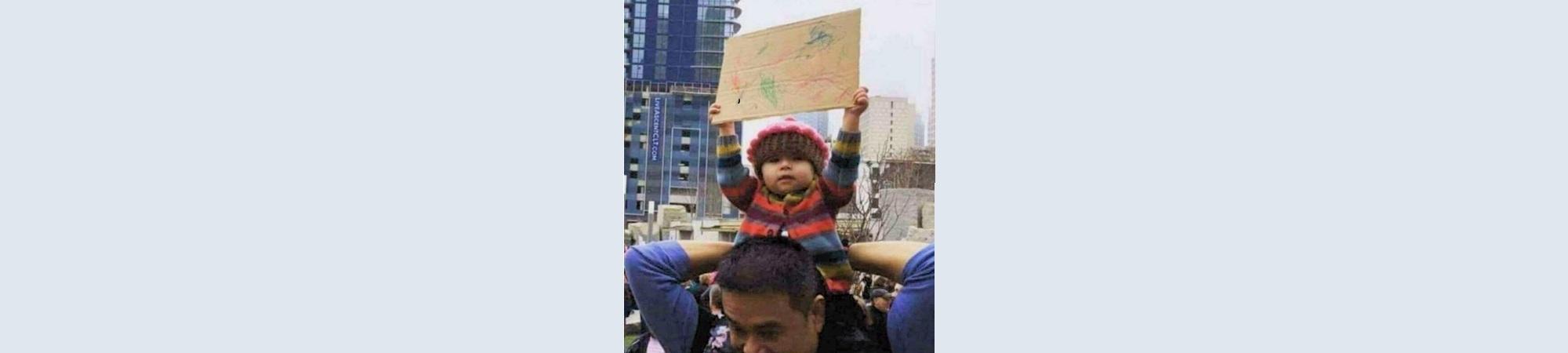 Child holding up scribbled sign in protest